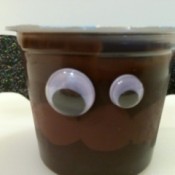 A chocolate pudding cup with bat wings and eyes.