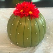 A faux cactus made from a pumpkin, pins and artificial flowers.